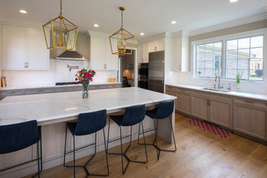 Inspiration for an u-shaped medium tone wood floor and brown floor eat-in kitchen remodel in Milwaukee with an undermount sink, shaker cabinets, medium tone wood cabinets, white backsplash, subway tile backsplash, stainless steel appliances, an island and white countertops