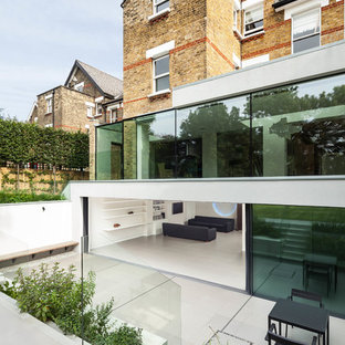 ロンドンのコンテンポラリースタイルのおしゃれな家の外観 (ガラスサイディング、陸屋根) の写真