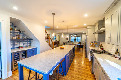 Inspiration for a mid-sized craftsman galley light wood floor and brown floor home bar remodel in Charlotte with recessed-panel cabinets, blue cabinets, granite countertops, white backsplash, ceramic backsplash and white countertops