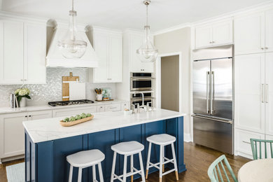 Inspiration for a mid-sized transitional l-shaped brown floor and medium tone wood floor kitchen remodel in Charlotte with a farmhouse sink, shaker cabinets, white cabinets, gray backsplash, an island, porcelain backsplash, stainless steel appliances, quartz countertops and white countertops