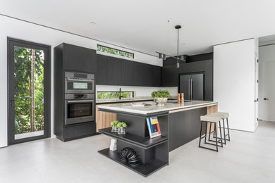 Inspiration for a mid-sized contemporary u-shaped ceramic tile and gray floor eat-in kitchen remodel in Miami with a single-bowl sink, flat-panel cabinets, black cabinets, onyx countertops, beige backsplash, marble backsplash, black appliances, an island and beige countertops