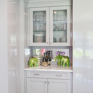 Inspiration for a small eclectic single-wall home bar in Philadelphia with glass-front cabinets, grey cabinets, marble benchtops, mirror splashback and medium hardwood floors.