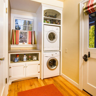 Ejemplo de cuarto de lavado lineal, tradicional, de tamaño medio, con puertas de armario blancas, armarios estilo shaker, encimera de cuarzo compacto, paredes beige, suelo de madera clara, lavadora y secadora apiladas, suelo beige y encimeras beige