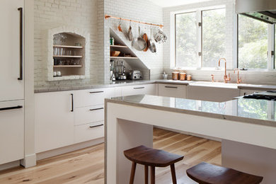 Trendy medium tone wood floor kitchen photo in Boston with a farmhouse sink, marble countertops, white backsplash, subway tile backsplash and stainless steel appliances