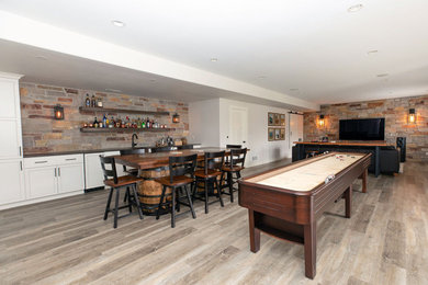 Example of a large mountain style walk-out vinyl floor, multicolored floor and brick wall basement design in Other with a bar and white walls
