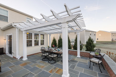 Backyard stone patio photo in Wilmington with a pergola