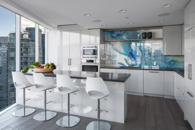 Contemporary l-shaped kitchen in Vancouver with an undermount sink, flat-panel cabinets, white cabinets, blue splashback, stainless steel appliances, dark hardwood floors, with island, brown floor and grey benchtop.
