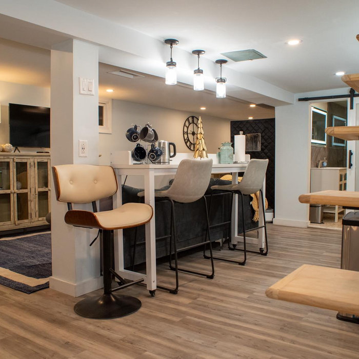 This stunning basement renovation transforms an unfinished space into a versatile, cozy retreat tailored for both relaxation and productivity. The open-concept design, featuring neutral tones, rich wo