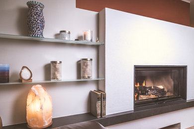 Kleines, Offenes Landhaus Wohnzimmer mit roter Wandfarbe, Terrakottaboden, Kaminofen, verputzter Kaminumrandung, freistehendem TV und rotem Boden in München