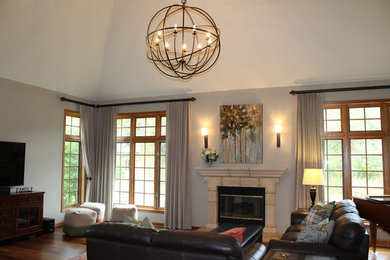 Example of a large transitional open concept medium tone wood floor and brown floor family room design in Milwaukee with gray walls, a standard fireplace, a stone fireplace and a tv stand