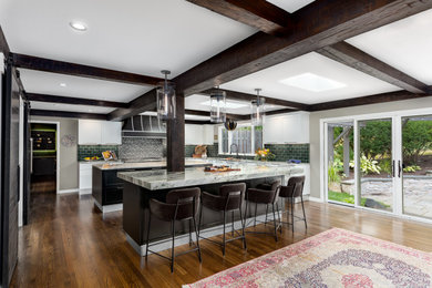 Large eclectic l-shaped medium tone wood floor, brown floor and exposed beam open concept kitchen photo in Detroit with an undermount sink, shaker cabinets, black cabinets, granite countertops, green backsplash, ceramic backsplash, stainless steel appliances, two islands and gray countertops