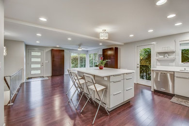 Photo of a mid-sized modern l-shaped open plan kitchen in Other with an undermount sink, flat-panel cabinets, grey cabinets, quartz benchtops, stainless steel appliances, dark hardwood floors, with island, brown floor and white benchtop.