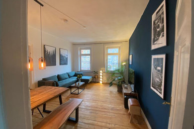 Mittelgroßes, Offenes Industrial Wohnzimmer mit blauer Wandfarbe, braunem Holzboden, freistehendem TV, braunem Boden, Holzdielendecke und Tapetenwänden in Hamburg