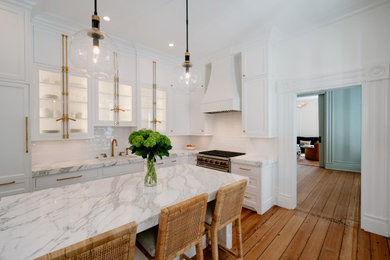 This is an example of a mid-sized transitional l-shaped eat-in kitchen in Charleston with an undermount sink, beaded inset cabinets, white cabinets, marble benchtops, white splashback, subway tile splashback, panelled appliances, medium hardwood floors, with island, brown floor and grey benchtop.