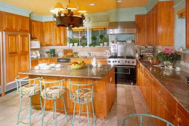 Foto på ett stort kök, med skåp i mellenmörkt trä, rostfria vitvaror och en köksö