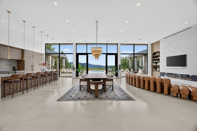 Huge trendy concrete floor and beige floor dining room photo in Montreal with white walls, a standard fireplace and a stone fireplace