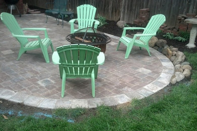 Example of a large backyard stone patio design in Omaha with no cover