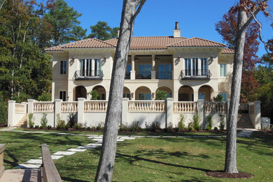 Large traditional beige two-story stucco exterior home idea in Other with a hip roof