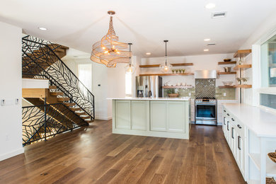 Large country l-shaped medium tone wood floor kitchen photo in Austin with a farmhouse sink, shaker cabinets, white cabinets, quartz countertops, green backsplash, ceramic backsplash, stainless steel appliances and an island