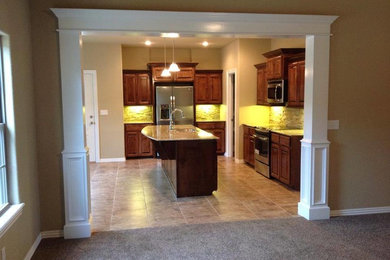 Small elegant l-shaped ceramic tile eat-in kitchen photo in Other with an undermount sink, raised-panel cabinets, dark wood cabinets, granite countertops, ceramic backsplash, stainless steel appliances, an island and beige backsplash