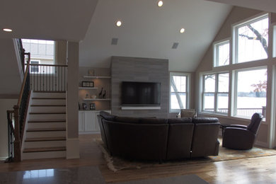 Diseño de sala de estar tipo loft actual grande con paredes blancas, suelo de madera clara y televisor colgado en la pared