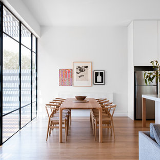 Contemporary open plan dining in Melbourne with white walls, light hardwood floors, no fireplace and beige floor.