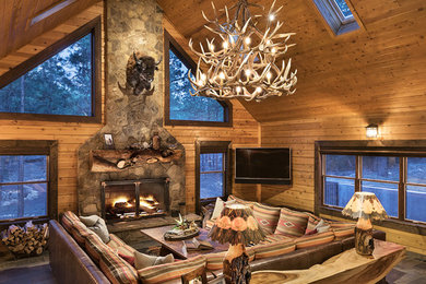 Mid-sized mountain style open concept slate floor and gray floor living room photo in Phoenix with brown walls, a standard fireplace, a stone fireplace and a wall-mounted tv