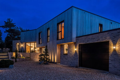 This is an example of a large contemporary two floor front detached house in Hampshire with wood cladding and board and batten cladding.
