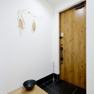 東京23区の片開きドアモダンスタイルのおしゃれな玄関ホール (白い壁、磁器タイルの床、木目調のドア、黒い床) の写真