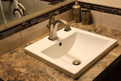Bathroom - small modern 3/4 brown tile and mosaic tile vinyl floor bathroom idea in Calgary with shaker cabinets, medium tone wood cabinets, a one-piece toilet, beige walls, a drop-in sink and laminate countertops