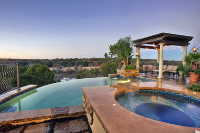 Hot tub - large rustic backyard concrete and custom-shaped infinity hot tub idea in Austin