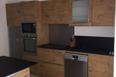 Cette photo montre une cuisine ouverte encastrable tendance en bois brun de taille moyenne avec un évier 1 bac, une crédence noire, îlot, un sol beige et un plan de travail marron.