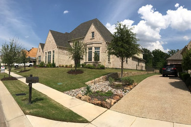 Large traditional two-storey beige house exterior in Dallas with stone veneer, a gable roof and a shingle roof.