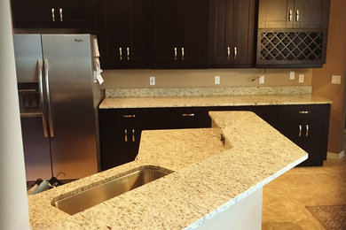 Inspiration for a mid-sized contemporary u-shaped ceramic tile eat-in kitchen remodel in Tampa with an undermount sink, granite countertops, stone slab backsplash, an island, black cabinets and stainless steel appliances