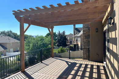 Large backyard second story metal railing deck photo in Salt Lake City with a pergola