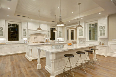 Elegant kitchen photo in Los Angeles with glass-front cabinets, white cabinets, white backsplash and two islands