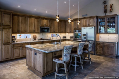Eat-in kitchen - large traditional l-shaped travertine floor eat-in kitchen idea in Phoenix with a double-bowl sink, raised-panel cabinets, light wood cabinets, granite countertops, beige backsplash, stone tile backsplash, stainless steel appliances and an island