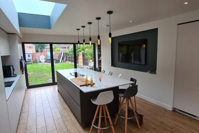 Photo of a large contemporary grey and white single-wall open plan kitchen in Other with flat-panel cabinets and an island.