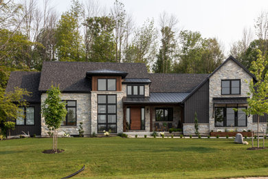 Exemple d'une façade de maison multicolore chic en planches et couvre-joints de taille moyenne et de plain-pied avec différents matériaux de revêtement, un toit à deux pans, un toit mixte et un toit noir.