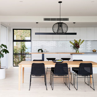 This is an example of a mid-sized modern open plan dining in Geelong with white walls, light hardwood floors and brown floor.