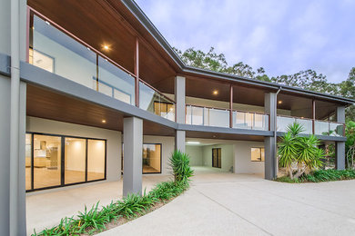 This is an example of a large contemporary two-storey beige house exterior in Brisbane with a flat roof.