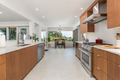 Example of a mid-sized 1950s u-shaped terrazzo floor and multicolored floor eat-in kitchen design in Vancouver with a double-bowl sink, flat-panel cabinets, medium tone wood cabinets, quartz countertops, white backsplash, subway tile backsplash, stainless steel appliances, no island and white countertops