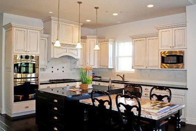 Inspiration for a large modern dark wood floor eat-in kitchen remodel in DC Metro with an integrated sink, flat-panel cabinets, black cabinets, granite countertops, white backsplash, ceramic backsplash, stainless steel appliances and an island