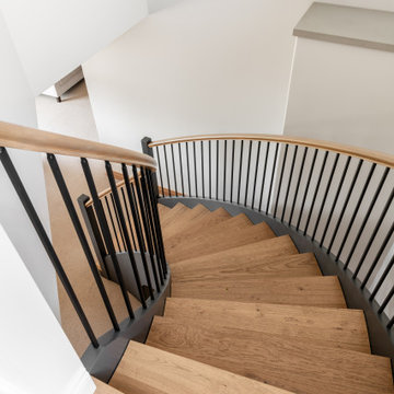 Curved Floating Wood Staircase with Black Metal Railing – Victoria BC Interior