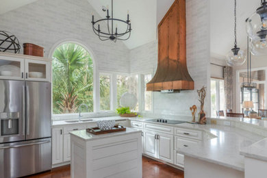 Example of a mid-sized beach style u-shaped dark wood floor and brown floor open concept kitchen design in Atlanta with a double-bowl sink, raised-panel cabinets, white cabinets, quartzite countertops, white backsplash, subway tile backsplash, stainless steel appliances, an island and gray countertops