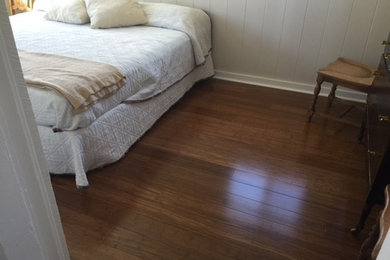 Example of a small beach style guest dark wood floor and brown floor bedroom design in Other with white walls