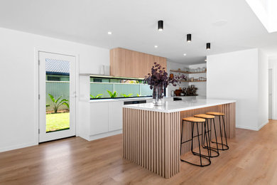 Design ideas for a mid-sized modern l-shaped kitchen pantry in Sunshine Coast with an undermount sink, solid surface benchtops, window splashback, black appliances, vinyl floors, with island, brown floor and white benchtop.