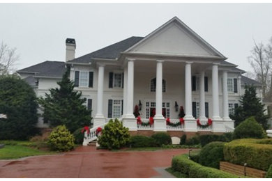 Expansive traditional two-storey stucco white house exterior in Atlanta with a clipped gable roof and a shingle roof.