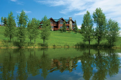 Large rustic brown three-story wood exterior home idea in Other with a metal roof