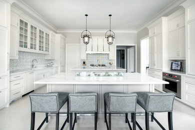 This is an example of an expansive traditional u-shaped kitchen/diner in Nashville with a submerged sink, beaded cabinets, white cabinets, quartz worktops, white splashback, marble splashback, stainless steel appliances, marble flooring, multiple islands, white floors and white worktops.